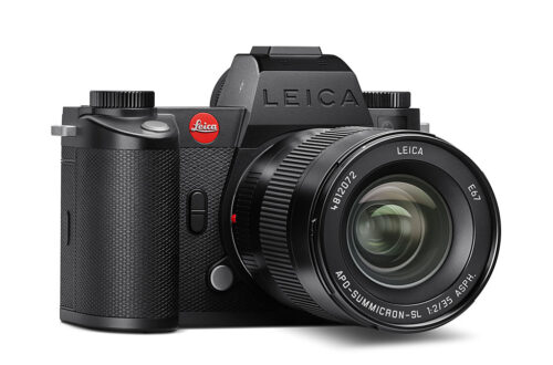 Black Leica mirrorless camera with lens on a white background.