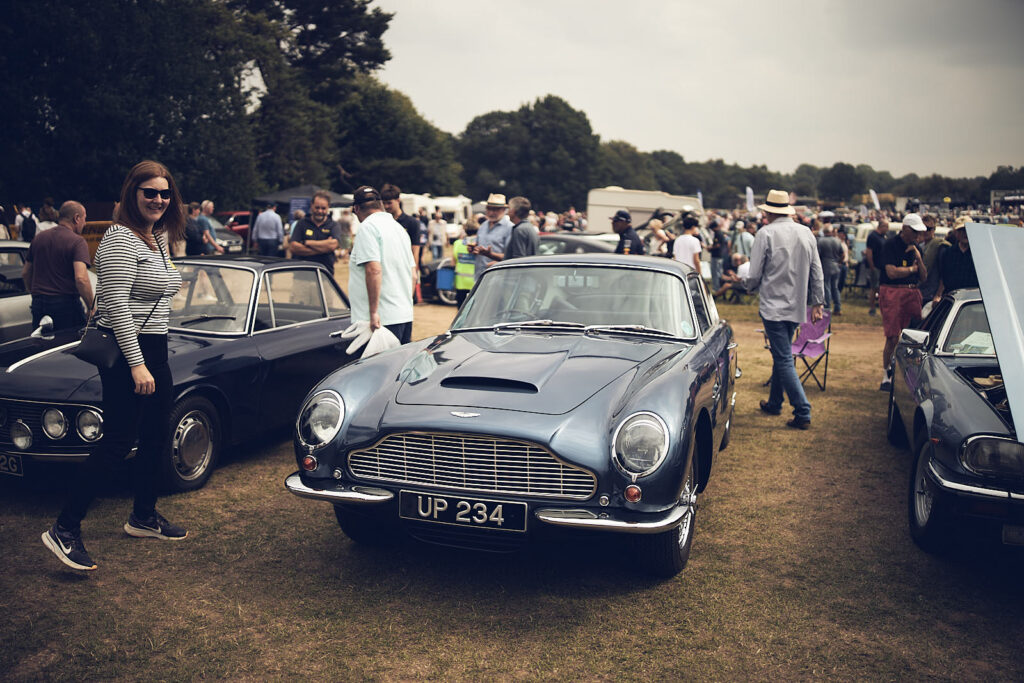 Aston DB 6 with a woman walking into the frame.