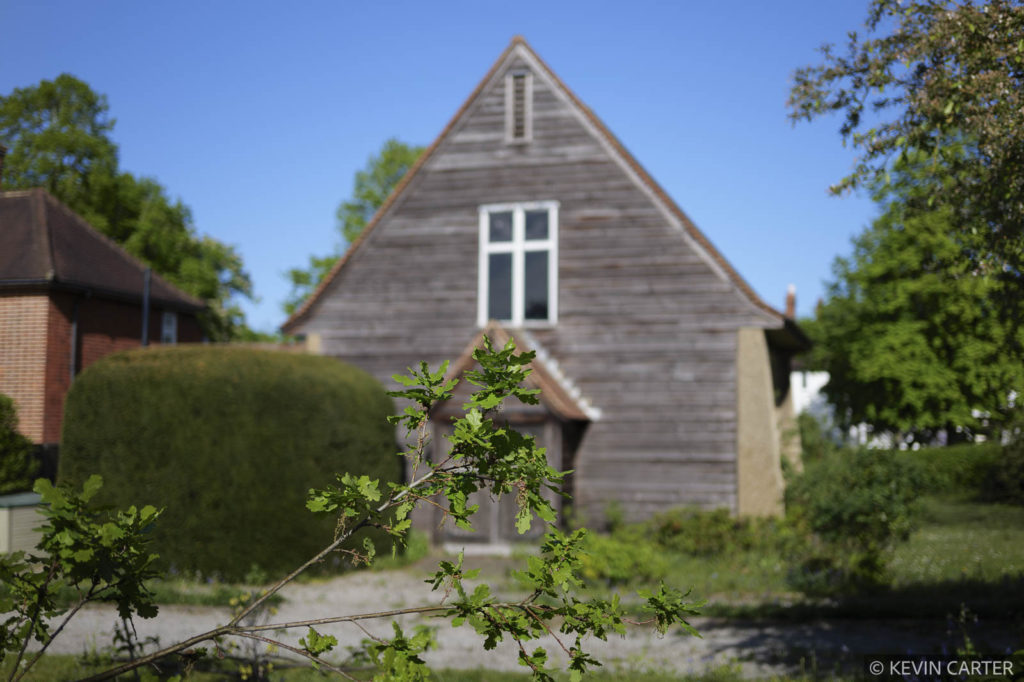 Foliage in front of a small Arts & Crafts style church  